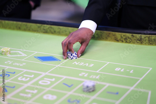 Hand croupier with chips on the gaming table in the casino