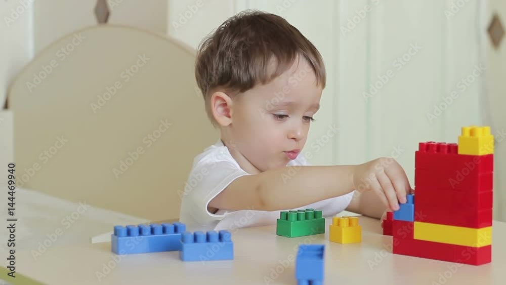 The child sitting at the table, playing with a contructor The child sitting at the table, playing with a contructor