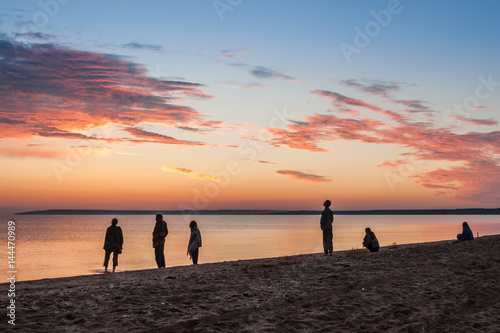 Beautiful colorful summer sea sunrise landscape with amazing colorful clouds in a blue sky and unrecognizable people silhouettes waiting for the Sun. In Crimea, Azov sea, Ukraine 2013.