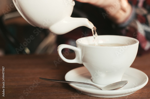 the girl in the cafe pours a cup of tea photo