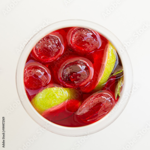 Cocktail drink with lime, orange, mint berries and ice in glass top view isolated