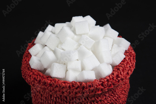 White sugar cubes in a red bag. Isolated on the black background.
