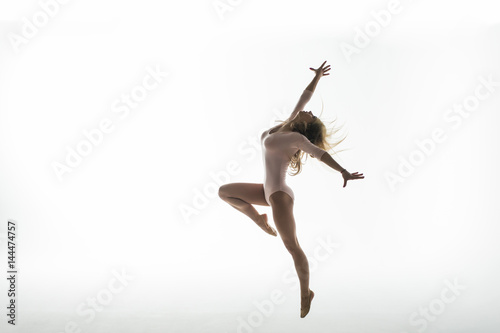 Fototapeta Naklejka Na Ścianę i Meble -  Young slim gymnast in studio on white background