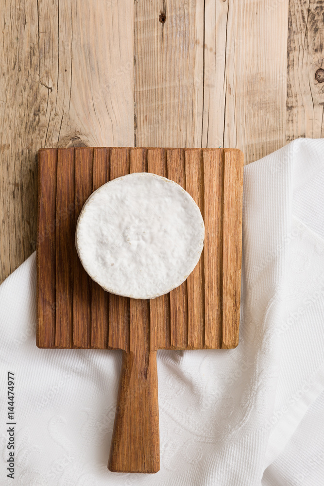 Top view on Camembert cheese on wooden board. Serving French homemade soft cheese. Food concept Top view on Camembert cheese on wooden board. Serving French homemade soft cheese. Food concept