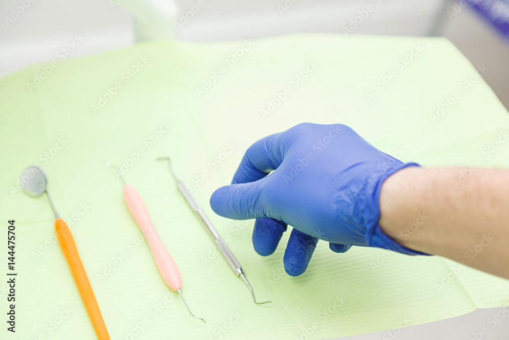Dentist's hand in a blue glove takes a tool Dentist's hand in a blue glove takes a tool