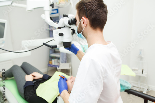 Male dentist is looking through a microscope