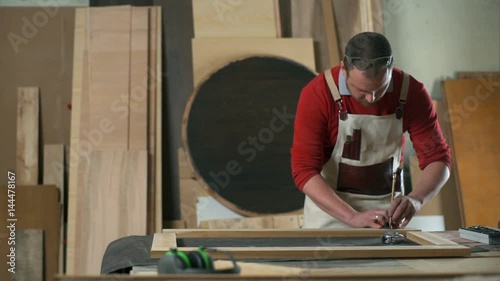 Carpenter leaving marks on a wooden plank with pencil in a workshop slow motion photo