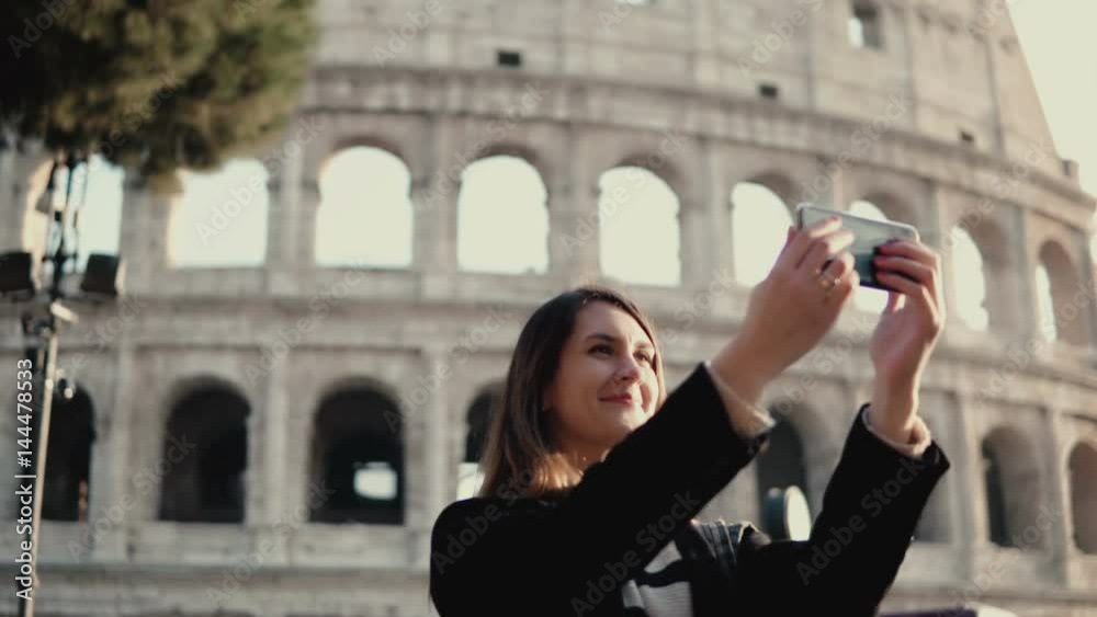Young beautiful woman takes the selfie on smartphone. Woman walking in Rome, Italy near the Colosseum. Young beautiful woman takes the selfie on smartphone. Woman walking in Rome, Italy near the Colosseum.