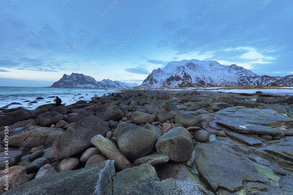 Ancient stones on the shores of cold Norwegian Sea at evening time. Lofoten islands. Beautiful Norway landscape.