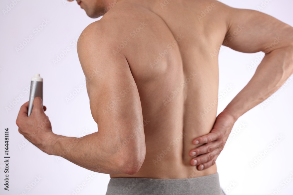 Fototapeta premium Man applying pain relieving cream, gel. Sport injury, Man with back, neck pain. Pain relief and health care concept.