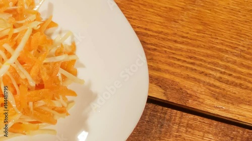 Vegetable salad of carrot and cabbage in white plate on wooden background close up. Vegetarian healthy salad in vegetable oil
