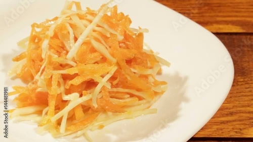 Vegetable salad of carrot and cabbage in white plate on wooden background close up. Vegetarian healthy salad in vegetable oil