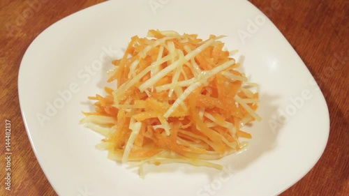 Vegetable salad of carrot and cabbage in white plate on wooden background close up. Vegetarian healthy salad in vegetable oil