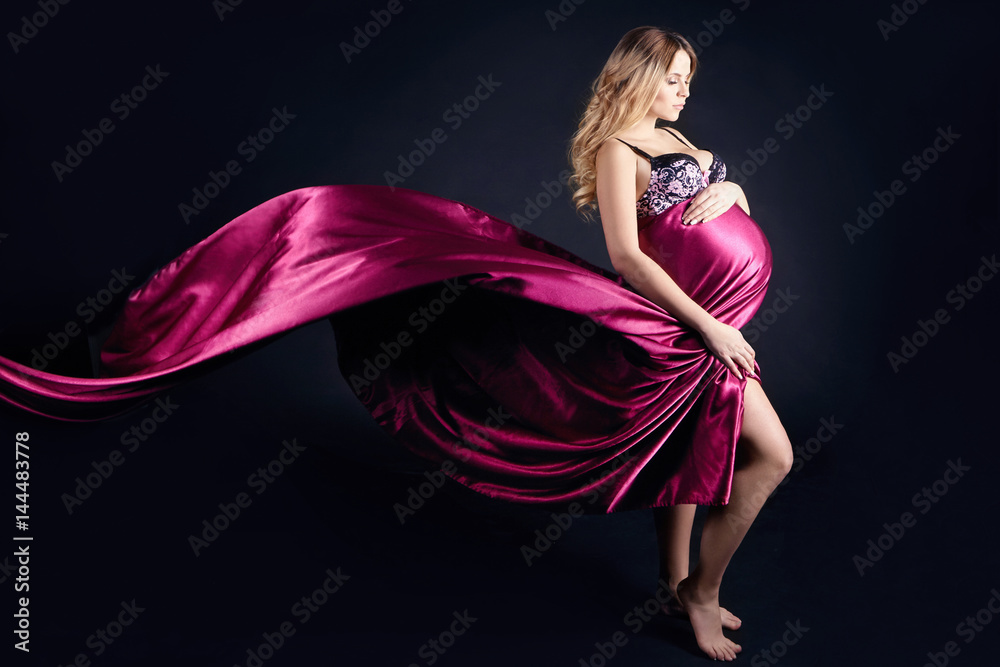 Pregnant woman in lingerie on gray background. A few days before birth. Beautiful  pregnant blonde woman waiting for the birth of the child. Expectant mother  Stock Photo