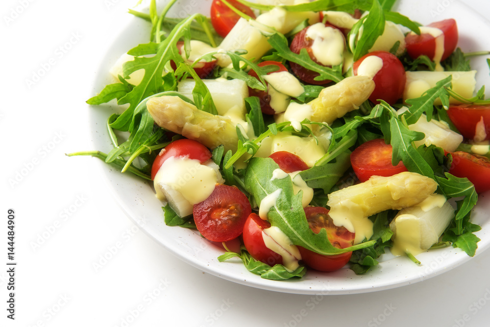 Salad of white asparagus, cocktail tomatoes and arugulaappetizer snack in italian colors on a white background, copy space Salad of white asparagus, cocktail tomatoes and arugulaappetizer snack in italian colors on a white background, copy space