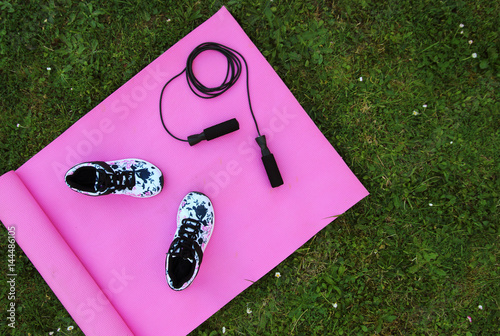 Mat yoga, women's shoes, jump rope on green grass, sports, fitness. The concept of a healthy lifestyle.