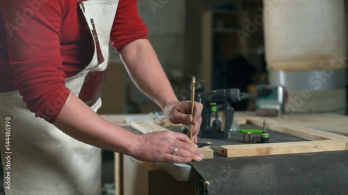 Carpenter making mark on a piece of wood with a pencil in a workshop slow motion photo