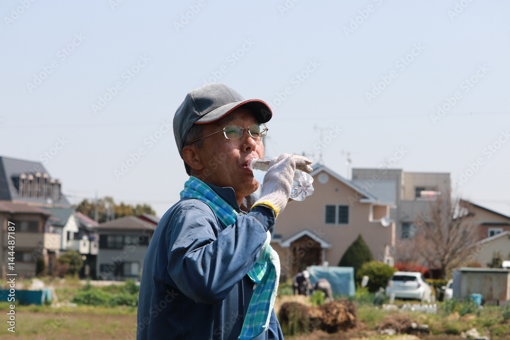 畑で水分補給するシニア 畑で水分補給するシニア