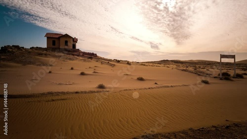 Static timelapse of an abandoned ghost town train station during a sandstorm while the sand is shifting in a landscape setting with dense scattered clouds in Southern Namibia close to LÌ_deritz, Kolmanskop.