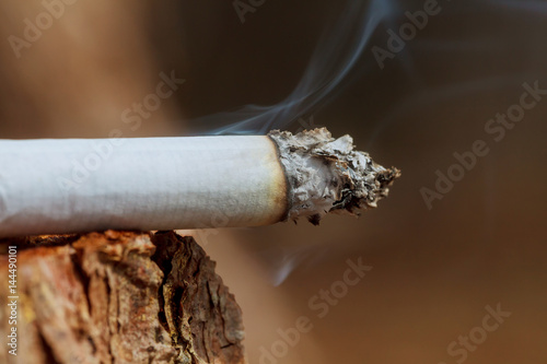 Cigarette with smoke on wooden background