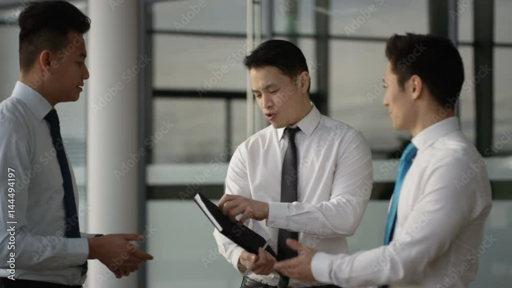 Businessmen talking shake hands in crowded area of large modern office Businessmen talking shake hands in crowded area of large modern office