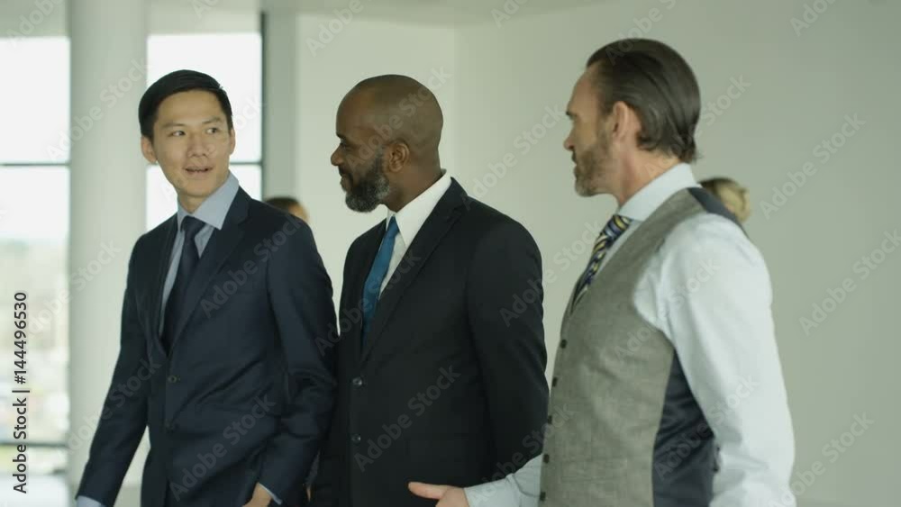 Cheerful business group chatting as they walk through busy modern office Cheerful business group chatting as they walk through busy modern office