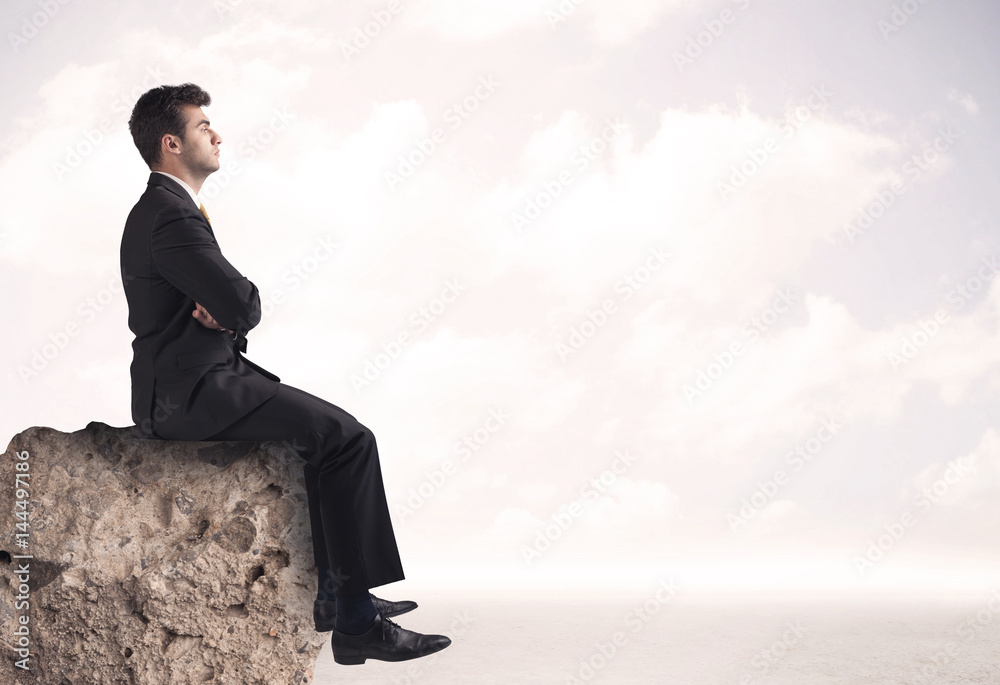 Business man sitting on stone edge Business man sitting on stone edge