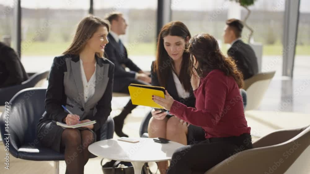 Female business team in discussion in busy meeting area of modern office Female business team in discussion in busy meeting area of modern office