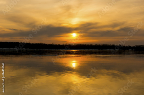 Yellow sunset reflected in the water surface of the river. River Ob, Novosibirsk, Russia. 8 April 2017