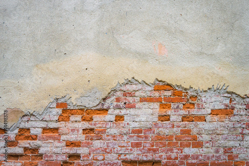 Grunge brick wall of the old house. Textured background. Remains of old plaster