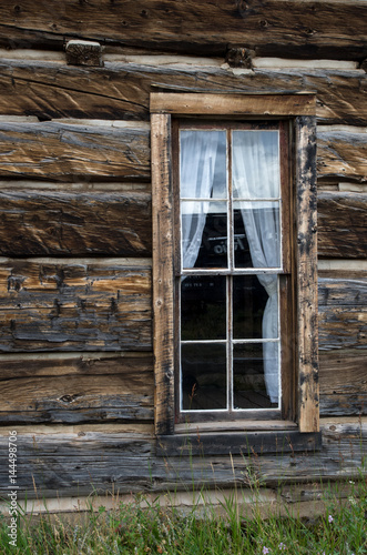 Old western house window with white curtains