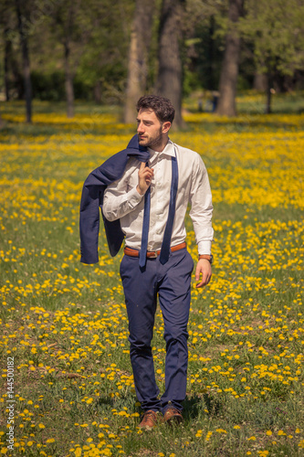 One young man, walking outdoors flowers field, suit formal clothes