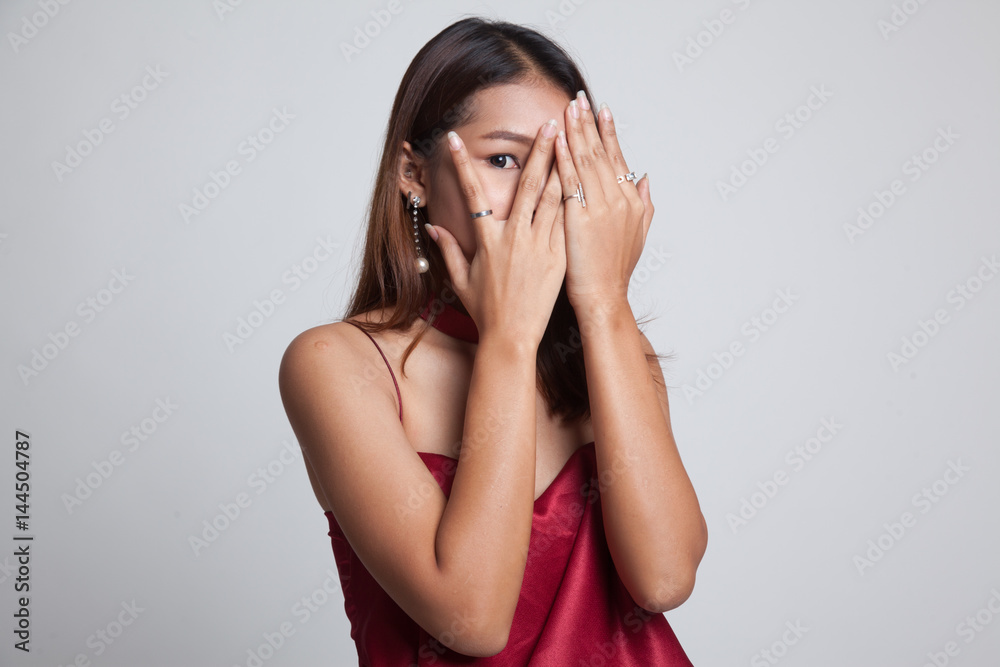 Beautiful young Asian woman peeking through fingers.
