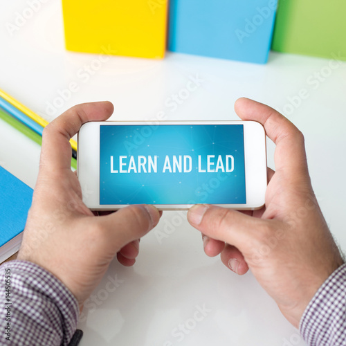 Man holding smartphone which displaying Learn and Lead
