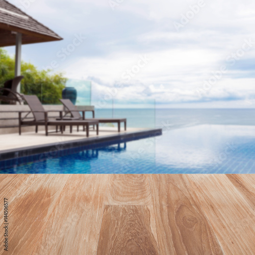 Wood table top on blur Beach chair in outdoor with swimming pool and sea view andaman sea.
