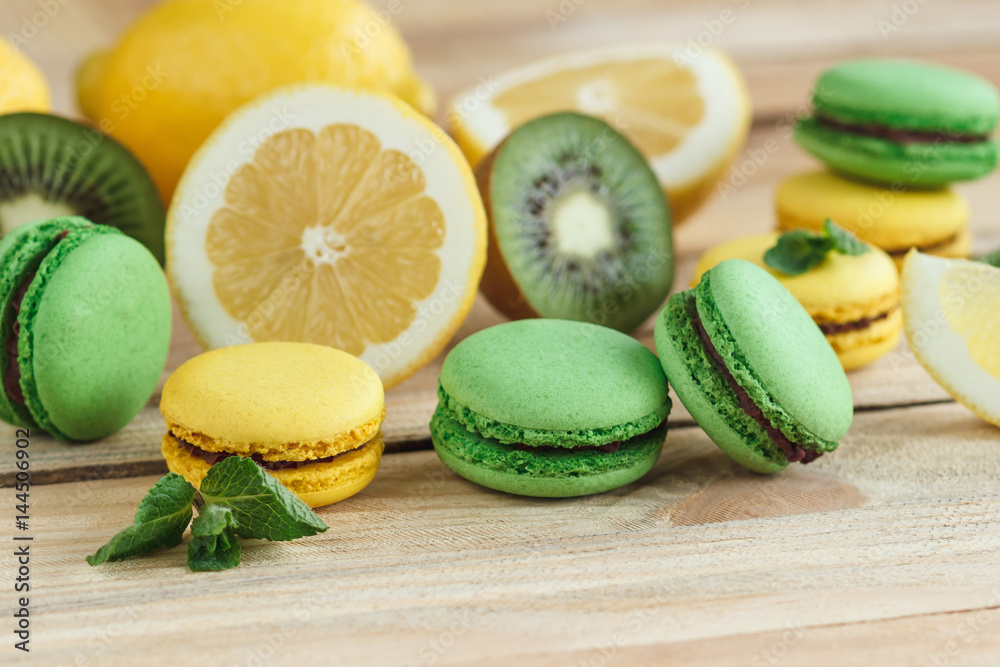 Green and yellow french macarons with kiwi, lemon and mint decorations Green and yellow french macarons with kiwi, lemon and mint decorations