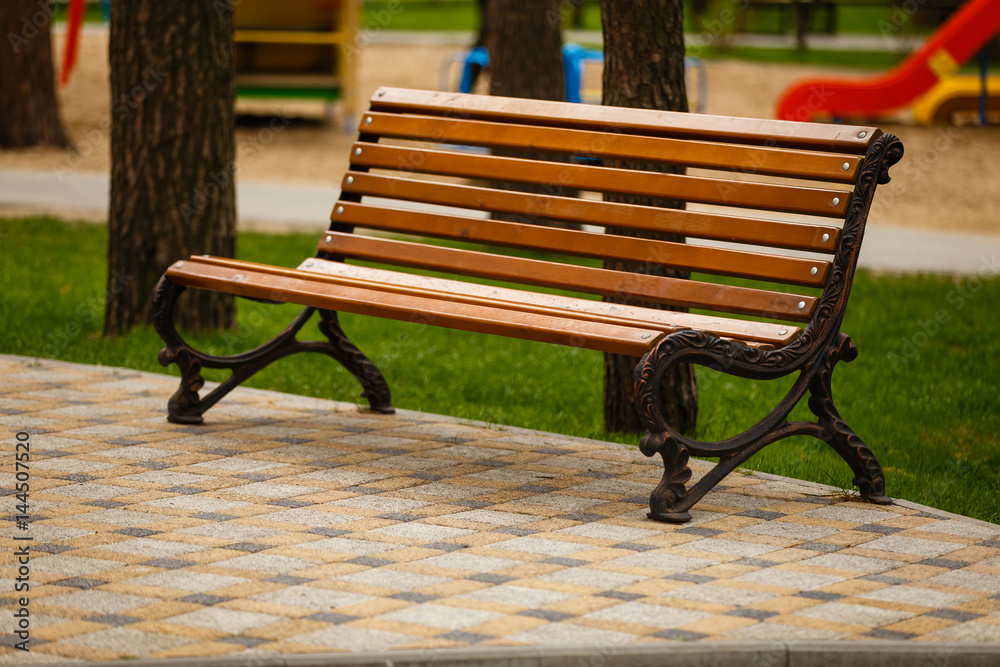 Close-up of wooden bench in park. Peaceful place with green grass. Close-up of wooden bench in park. Peaceful place with green grass.