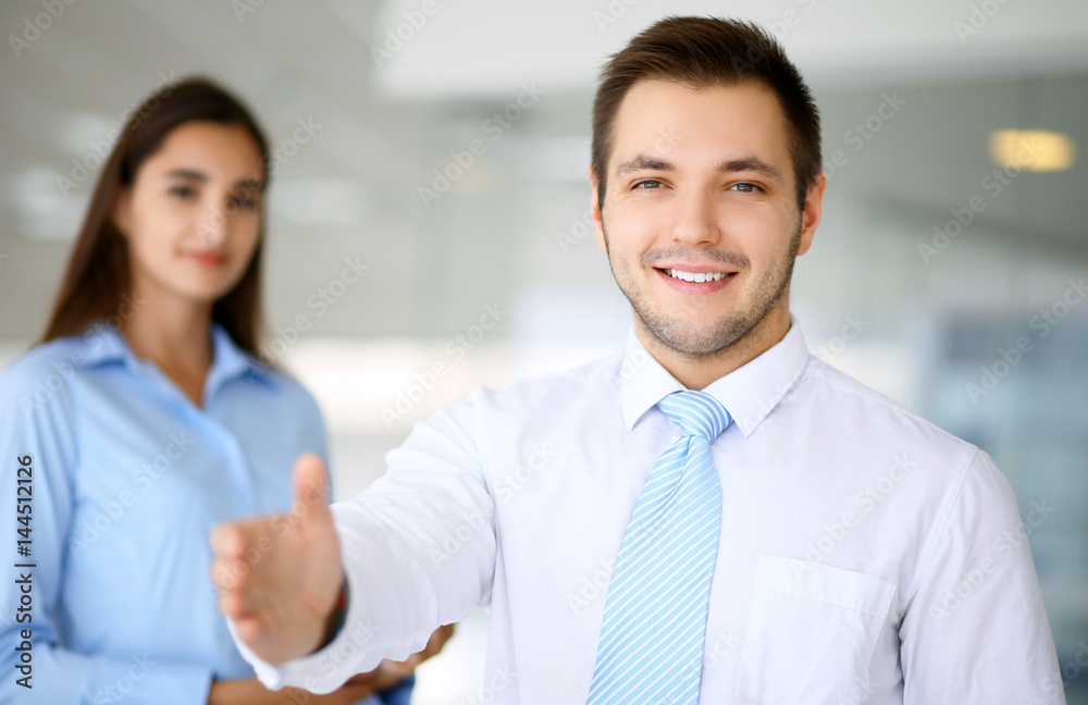 Smiling businessman in office with colleagues in the background Smiling businessman in office with colleagues in the background