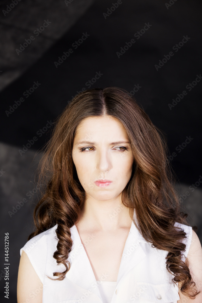 Very sad, unhappy and upset woman in white shirt, studio shoot  on dark background