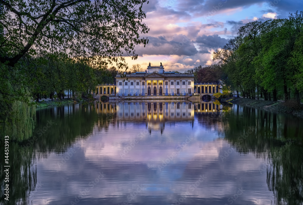 Obraz premium Pałac na Wyspie, Łazienki Królewskie. A Neoclassicist palace in Warsaw - an evening view with a cloudy reflection.