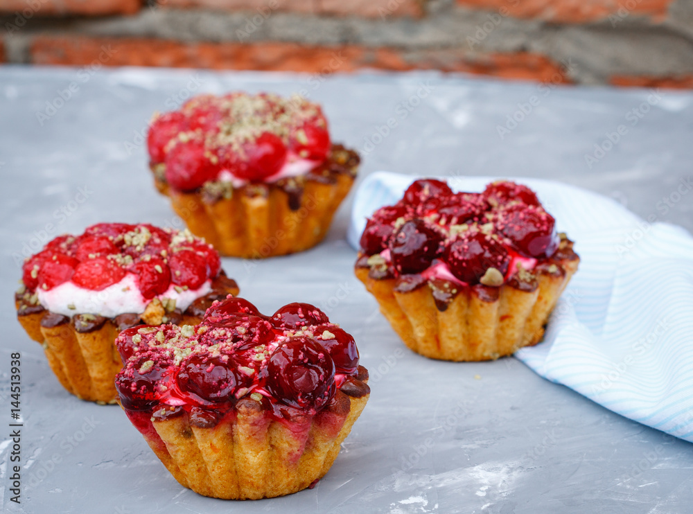 Homemade cake of sweet berry baskets with cherries and raspberries on the background of a peeling wall.