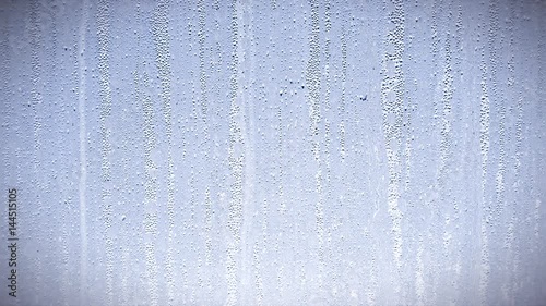 Raindrops trickling down glass in window