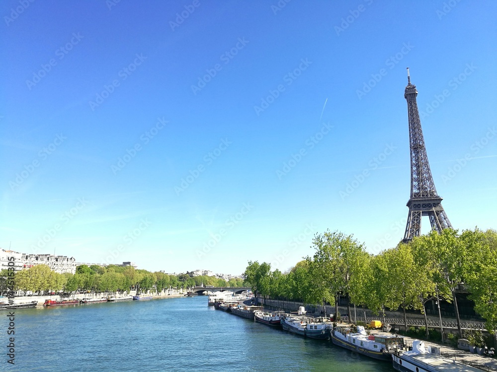 PARIS, FRANCE -APRIL 12, 2017 : spring view of Eiffel tower along the Seine river gate, and boats in tje seine river.