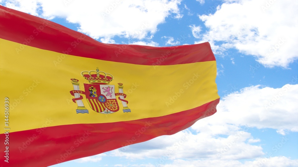 Waving flag of Spain on the blue cloudy sky.