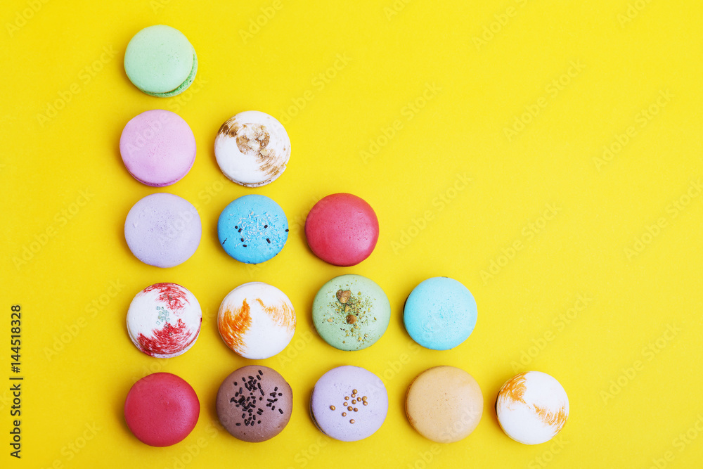 Tasty different colored macarons  on yellow background