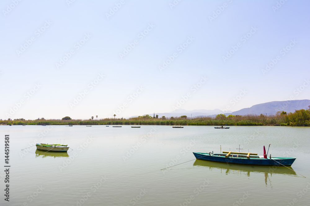 Fototapeta premium Calm lake with two fishing boats. Fresh water lagoon in Estany de cullera. Valencia, Spain