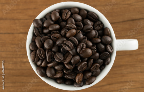 coffee beans in coffee cup on table wood background