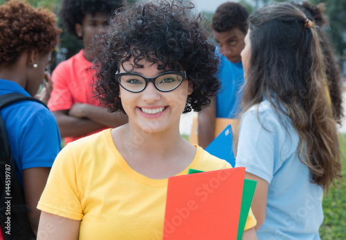 Smart caucasian female students with glasses and group of international students