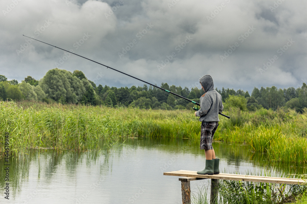 Teen boy fishing on wooden pier Teen boy fishing on wooden pier