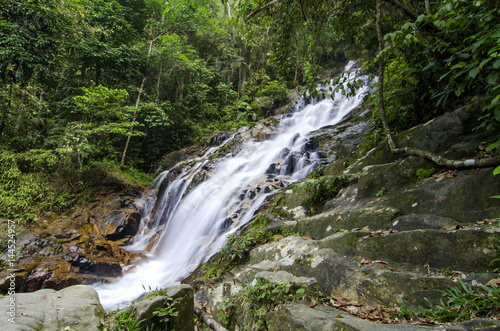 beautiful in nature, amazing cascading tropical waterfall. wet and mossy rock, surrounded by green rain forest